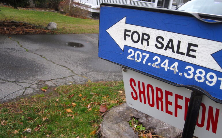A sign has an arrow that points to a house.