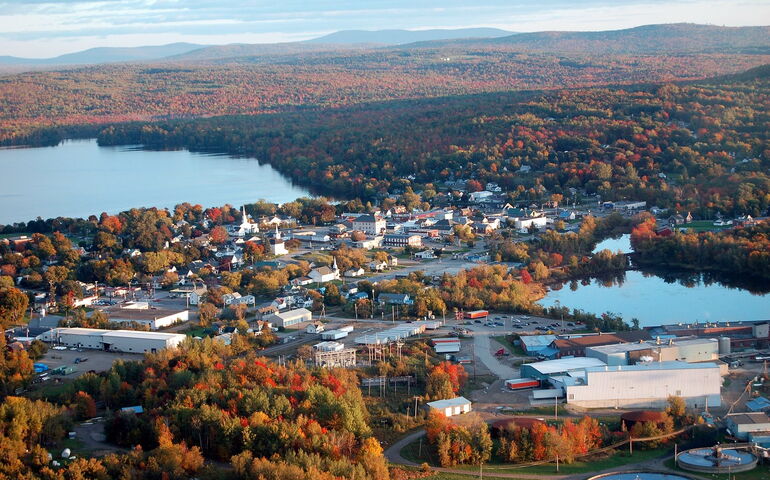 An aerial view shows woods, water and structures.