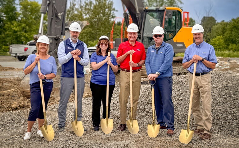 Six people pose in a line with shovels.
