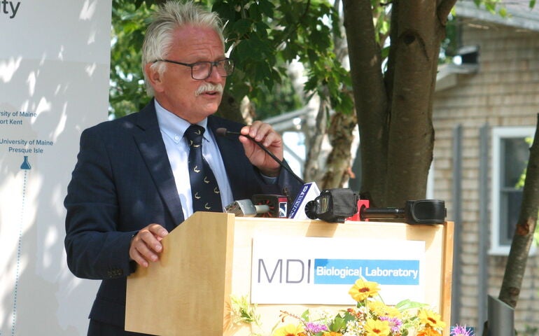 A person stands at a lectern with a mic.