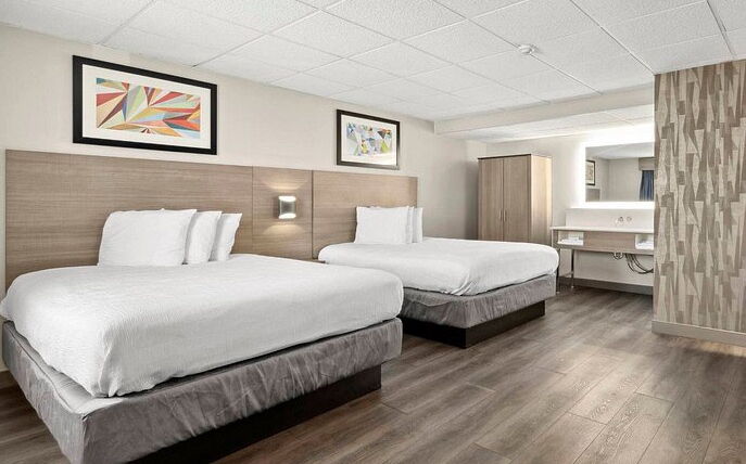 A room hs two beds and two framed prints.