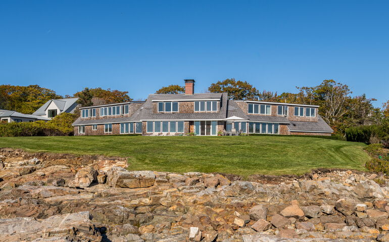 An exterior view shows a house with a lawn and rocks.