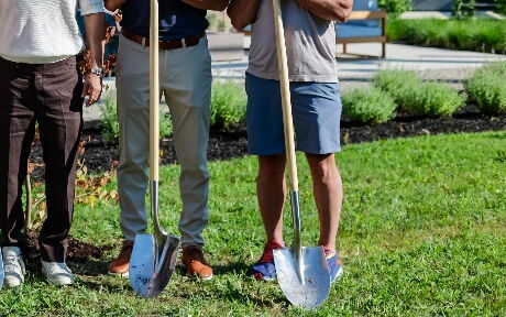 Five pose in a line with shovels.