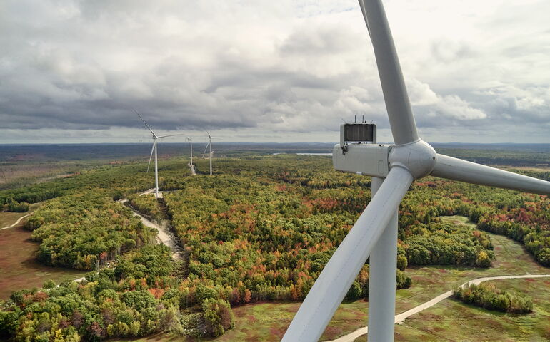 An aerial view of wind turbines and woods and fields.