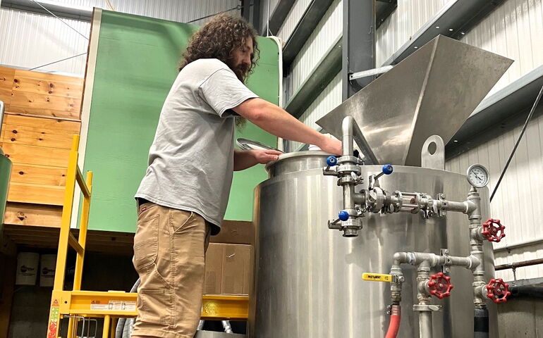 A person works at a metal tank.