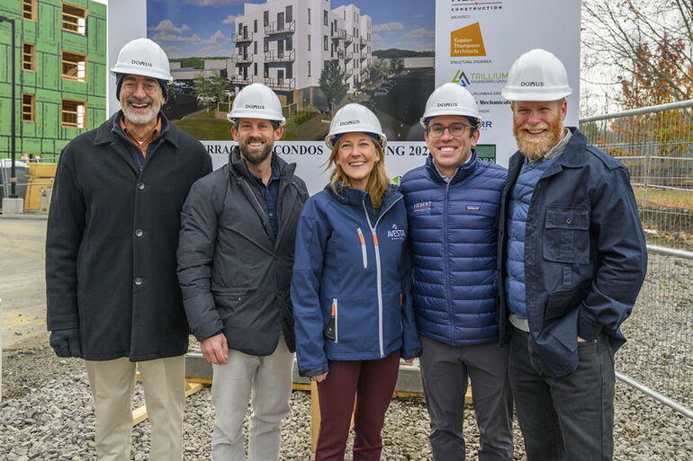 five people standing in front of a rendering 