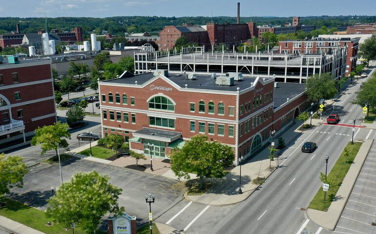 An aerial view shows a three-story brick building and streets.
