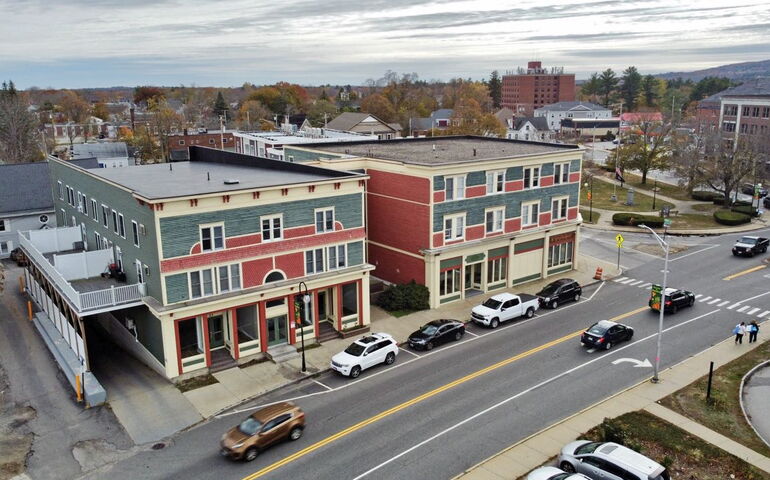 An aerial view shows two buildings and cars on a street.