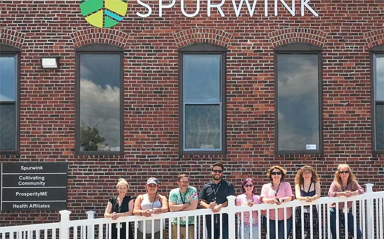 People stand in a line outside a brick building.
