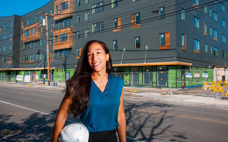 Rebecca Hatfield holding a hard hat in front of a building site 