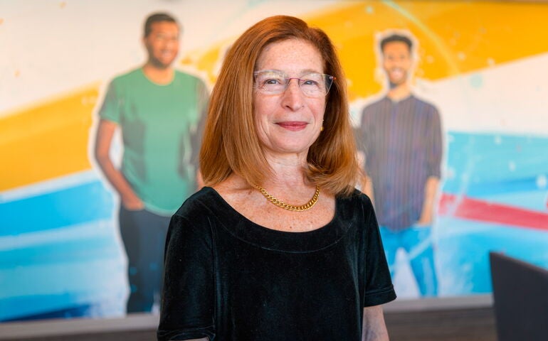 Leslie Hyman standing in front of a mural showing three people.