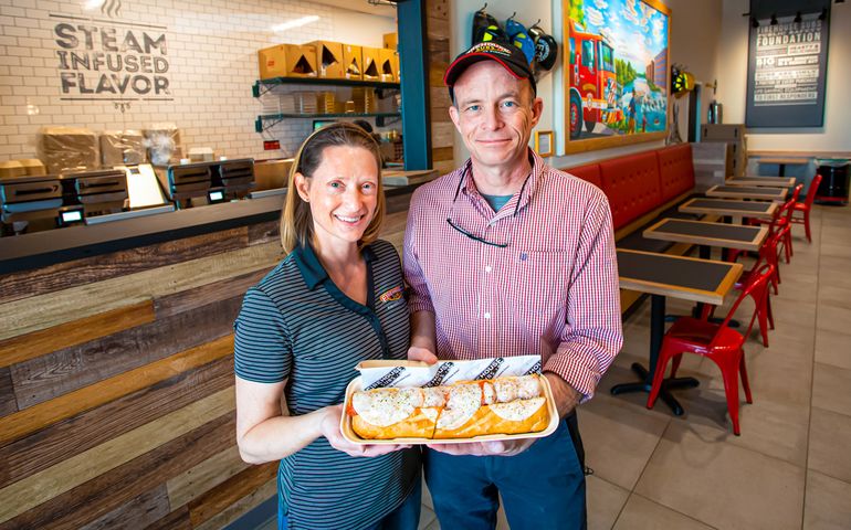 Couple who owns Firehouse Subs holding up a sandwich