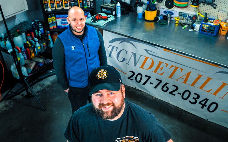 two men standing in front of car mechanic's bench