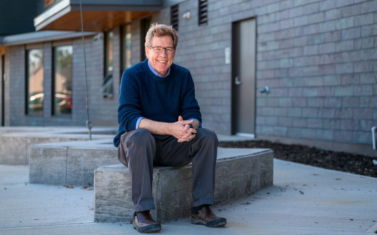 man in blue sweater sitting on a bench