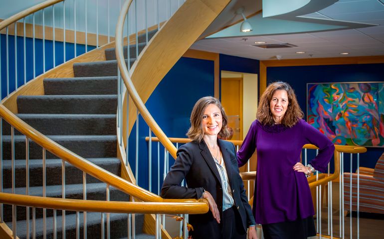 two women standing next to staircase