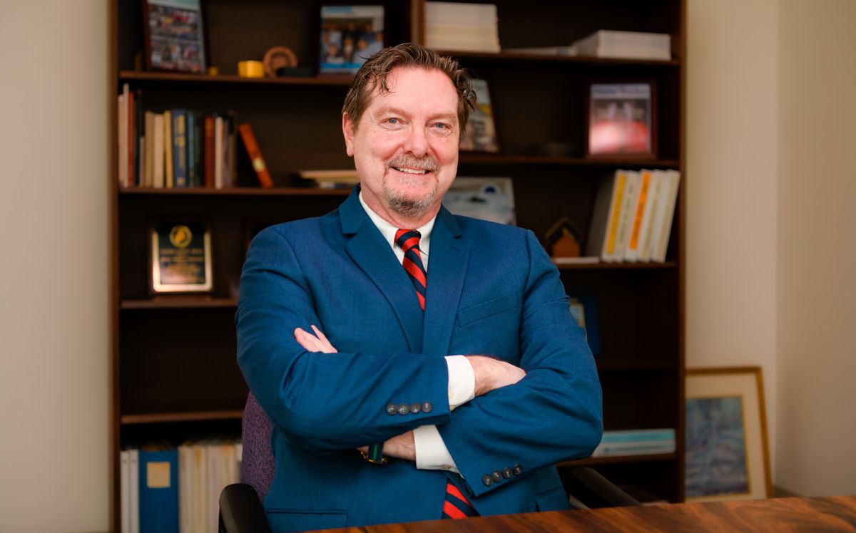 Jim Roche in his office, sitting down with his arms crossed in front of him.