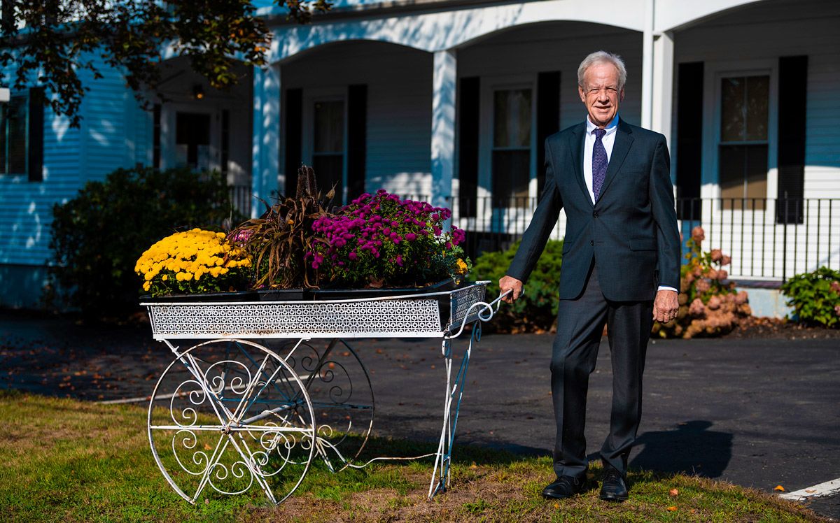 man in a suit standing outside next to a cart with flowers in it