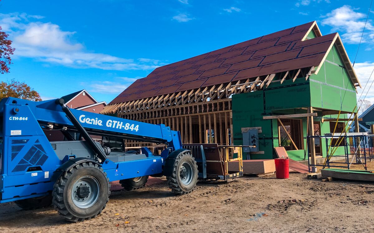 large building under construction, with blue construction vehicle in front